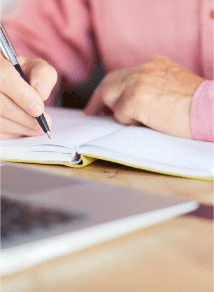 Person writing on a notebook with a pen