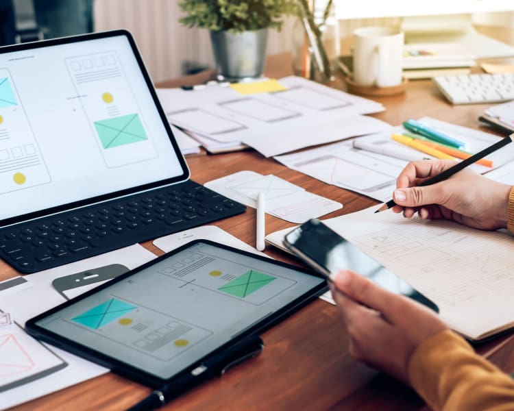 On-Page-Optimization-User-Experience-Design-Website A person focused on a laptop, using a tablet and pen to design a responsive layout.