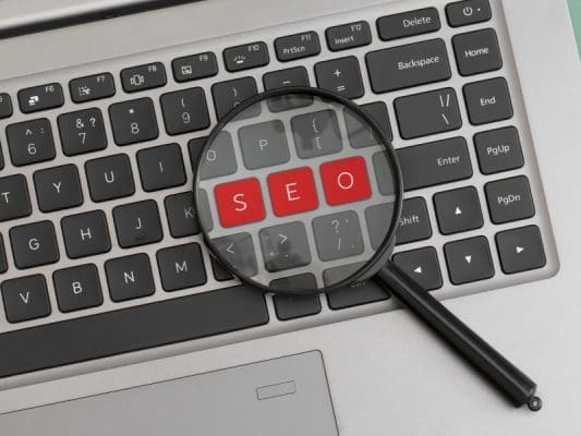 Keyboard with a magnifying glass highlighting the word seo in red
